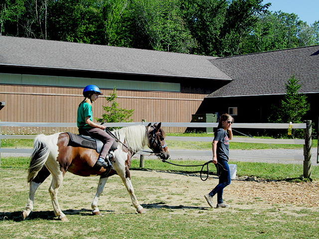 Hiram House Camp Horseback Riding Hiram House instructor walking rider on horse
