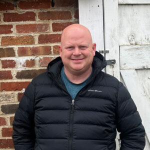 Portrait of Ben Sebastian in front of a small brick building